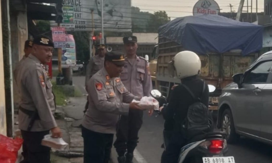 Personel Polsek Piyungan membagikan takjil gratis kepada pengendara di Simpang Tiga Piyungan Bantul saat Ramadhan 2026